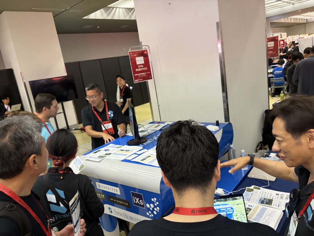 IVS会場で展示したシンロボ実機を囲んで、シンロボ社スタッフが来場者に説明をしている様子